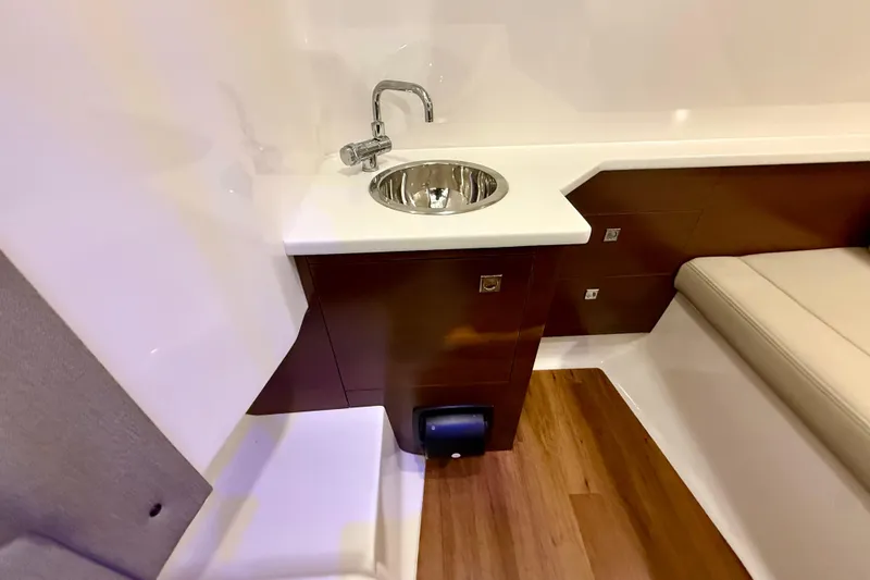 Slide: The Image of 2021 Chaparral 280 OSX interior with sink, wooden cabinetry, and cushioned seating. - 43