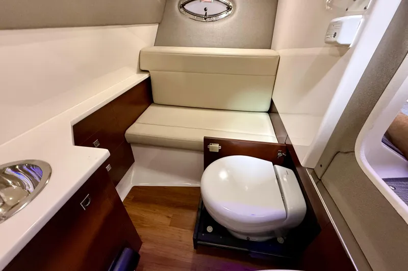 Slide: The Image of 2021 Chaparral 280 OSX boat interior with compact bathroom and seating area. - 45