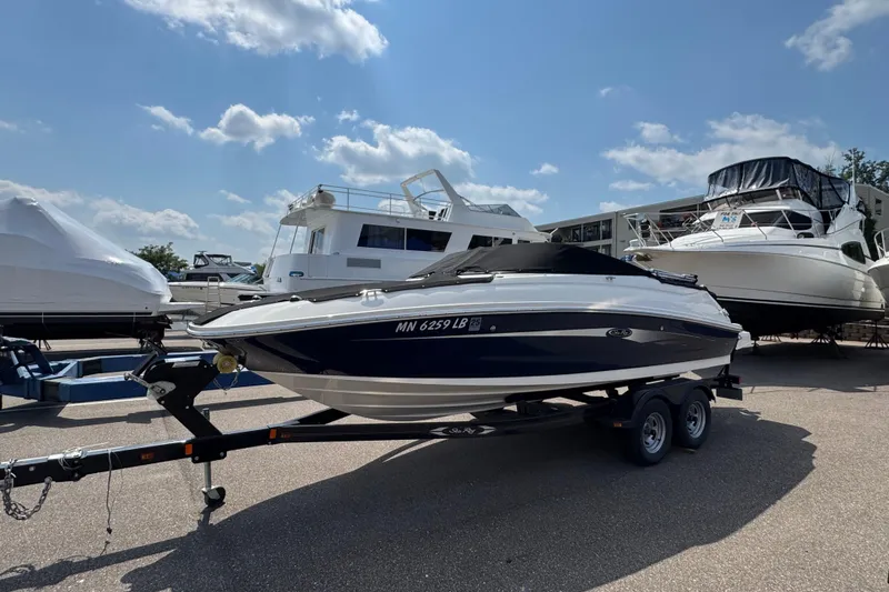 Slide: The Image of 2014 Sea Ray 220 Sundeck Outboard boat on trailer under a sunny sky. - 1