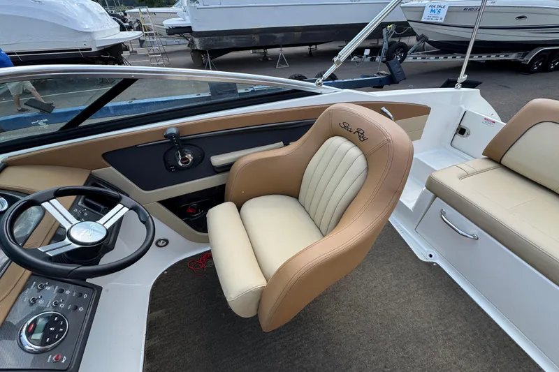 Slide: The Image of 2014 Sea Ray 220 Sundeck Outboard interior with tan seating and steering wheel. - 11