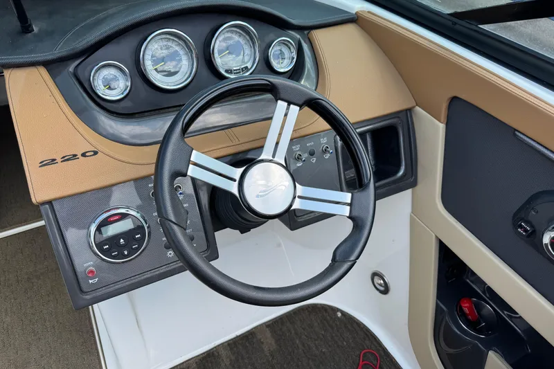 Slide: The Image of 2014 Sea Ray 220 Sundeck Outboard dashboard with steering wheel and gauges. - 12