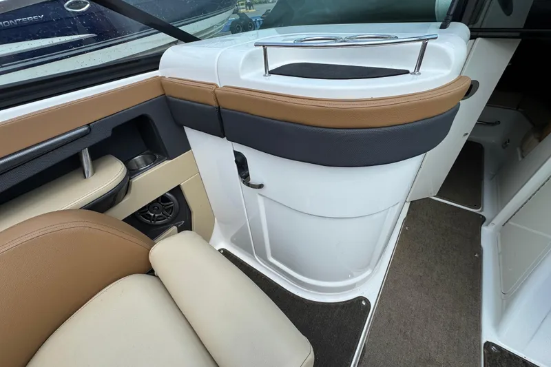 Slide: The Image of 2014 Sea Ray 220 Sundeck Outboard interior with tan and black seating, cup holder, and speaker. - 14