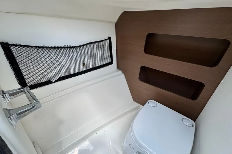 Slide: The Image of 2014 Sea Ray 220 Sundeck Outboard interior with storage net and portable toilet. - 16