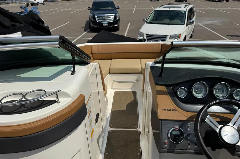Slide: The Image of 2014 Sea Ray 220 Sundeck Outboard interior with dashboard and seating, parked in a lot. - 17