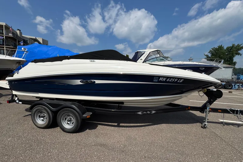 Slide: The Image of 2014 Sea Ray 220 Sundeck Outboard boat on trailer under blue sky. - 2