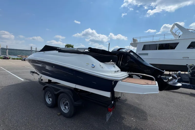 Slide: The Image of 2014 Sea Ray 220 Sundeck Outboard on trailer, parked in a lot under a blue sky. - 4