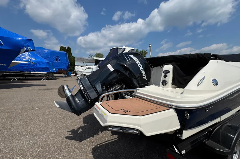 Slide: The Image of 2014 Sea Ray 220 Sundeck Outboard with Mercury engine, parked outdoors under a blue sky. - 6