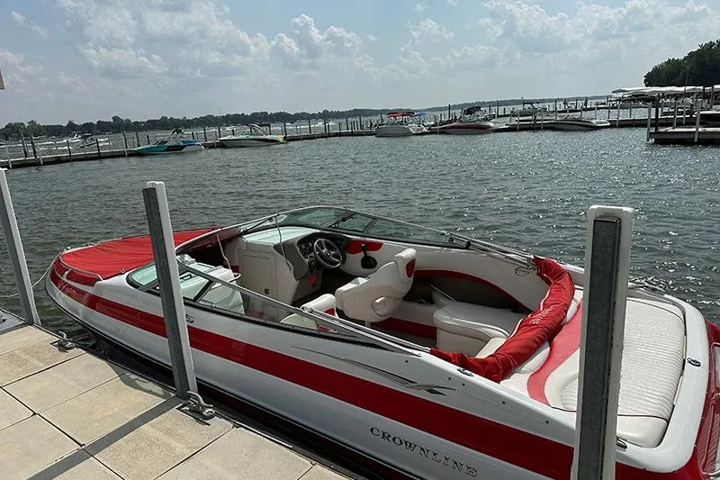 The Image of 2006 Crownline 266 boat docked at a marina, featuring red and white upholstery. - 1