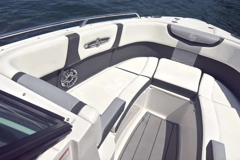 Slide: The Image of 2024 Chaparral 26 Surf boat interior with white and gray seating, on calm water. - 14
