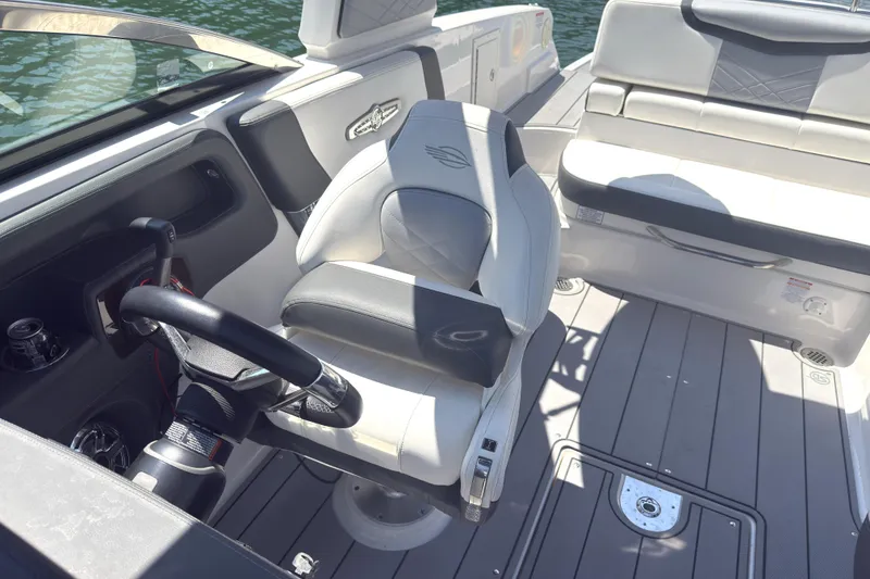 Slide: The Image of 2024 Chaparral 26 Surf boat interior with steering wheel and seating, on a sunny day. - 18