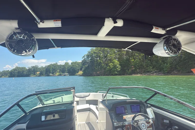 Slide: The Image of 2024 Chaparral 26 Surf boat interior with speakers, dashboard, and scenic lake view. - 20