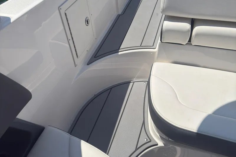 Slide: The Image of 2024 Chaparral 26 Surf boat interior with white seating and storage compartment. - 21