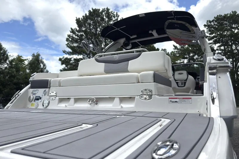 Slide: The Image of 2024 Chaparral 26 Surf boat, rear view, showcasing seating and deck details under a blue sky. - 5
