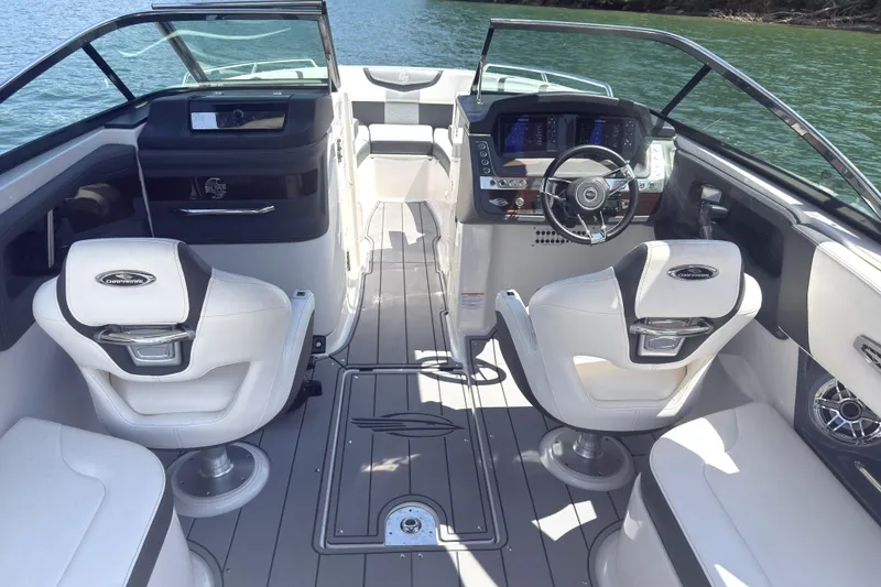 Slide: The Image of 2024 Chaparral 26 Surf boat interior with modern dashboard and seating on a lake. - 7