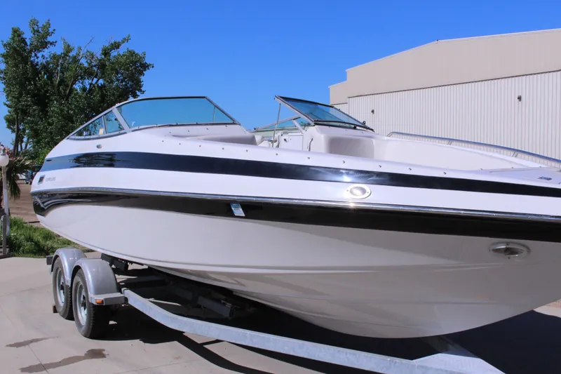 The Image of 2005 Crownline 266 BR boat on trailer, parked outdoors under clear blue sky. - 1