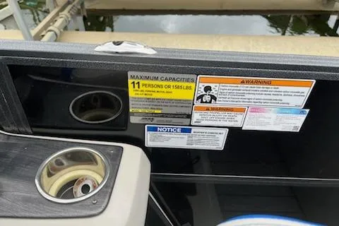 Slide: The Image of 2018 Misty Harbor S2385SU boat capacity and warning labels near cup holder. - 11