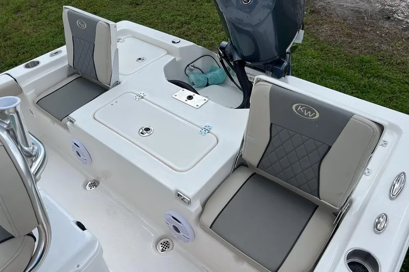 Slide: The Image of 2026 Key West 210 Bay Reef boat's rear view, featuring motor and trim tab on grass. - 18
