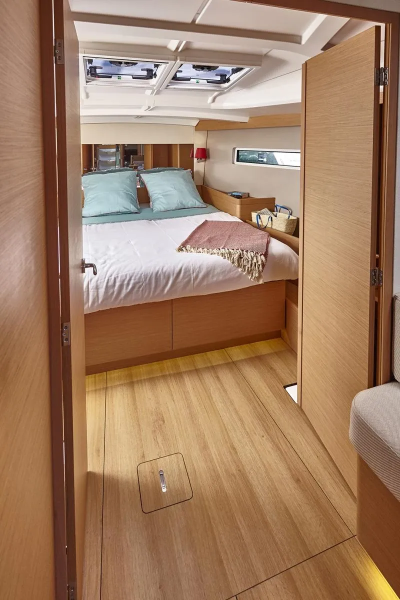Slide: The Image of 2023 Jeanneau Sun Odyssey 440 cabin interior with bed, wooden flooring, and skylights. - 13