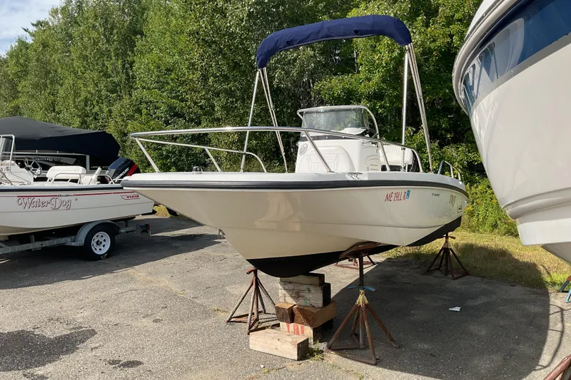 Slide: The Image of 2014 Boston Whaler 170 Dauntless boat on stands, surrounded by trees and other boats. - 3