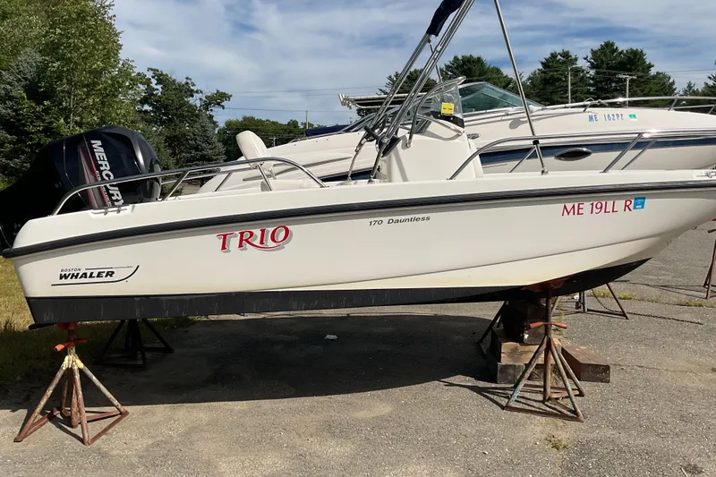Slide: The Image of 2014 Boston Whaler 170 Dauntless boat on stands, featuring a Mercury engine. - 7