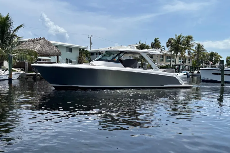 Slide: The Image of 2019 Tiara Sport 38 LS boat on calm water, surrounded by palm trees and waterfront homes. - 2