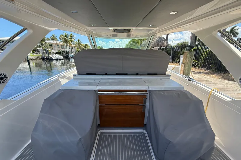 Slide: The Image of 2019 Tiara Sport 38 LS boat interior with covered seating and cabinetry, dockside view. - 21