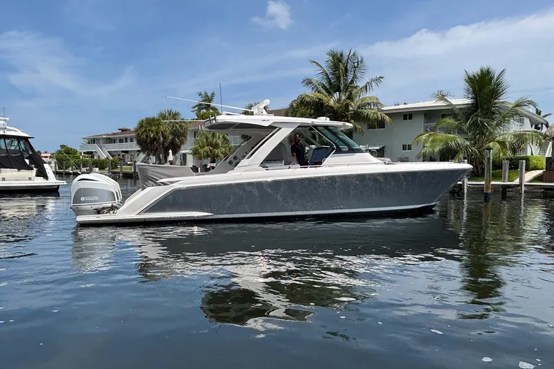 Slide: The Image of 2019 Tiara Sport 38 LS boat on calm water, surrounded by palm trees and buildings. - 35
