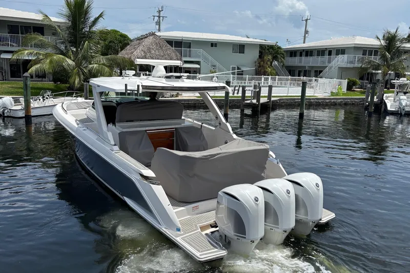 Slide: The Image of 2019 Tiara Sport 38 LS boat docked in a marina with triple outboard engines. - 4