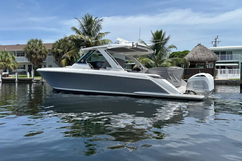 Slide: The Image of 2019 Tiara Sport 38 LS boat on calm water, with palm trees and houses in the background. - 5