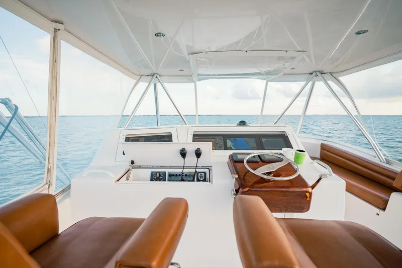 Slide: The Image of 2005 Viking 48 Convertible yacht helm with ocean view, featuring leather seats and navigation controls. - 48