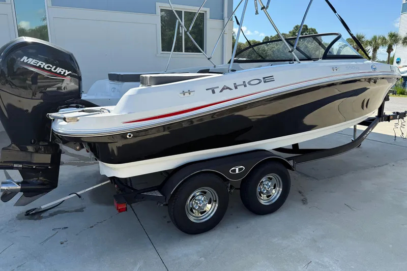 The Image of 2021 Tahoe 550 TS boat on trailer with Mercury outboard motor, parked outdoors. - 1