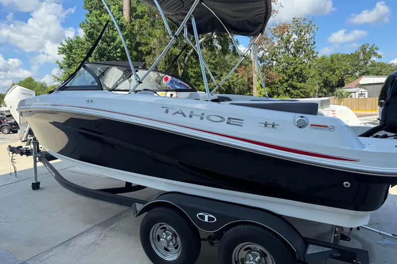 Slide: The Image of 2021 Tahoe 550 TS boat on trailer, black and white design, parked outdoors. - 2
