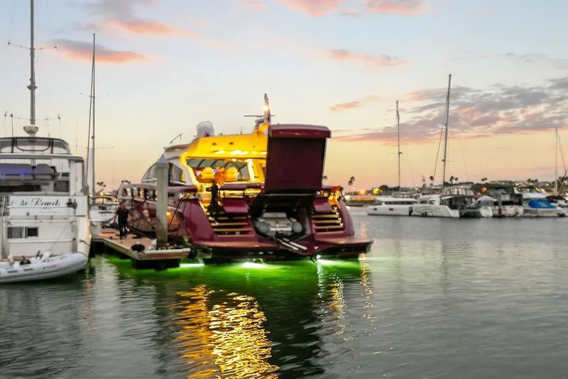 Slide: The Image of Luxury Baia yacht docked at sunset, illuminated with green underwater lights. - 2