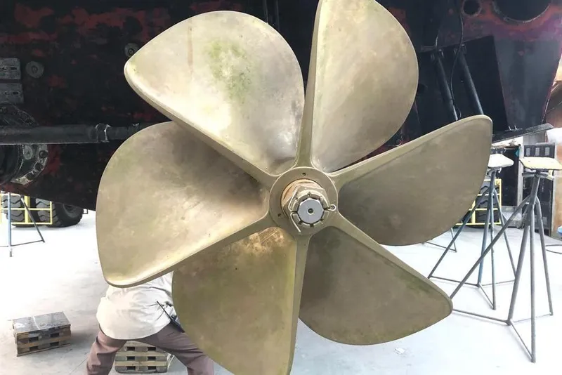 Slide: The Image of Large brass propeller of a 2011 Baia ONE HUNDRED yacht in a workshop setting. - 67