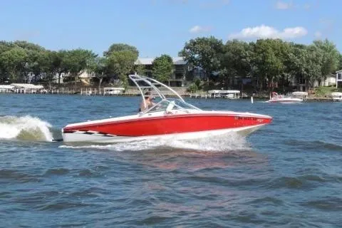 The Image of Red Centrian C4 boat cruising on a lake, 2004 model, with trees and houses in the background. - 1