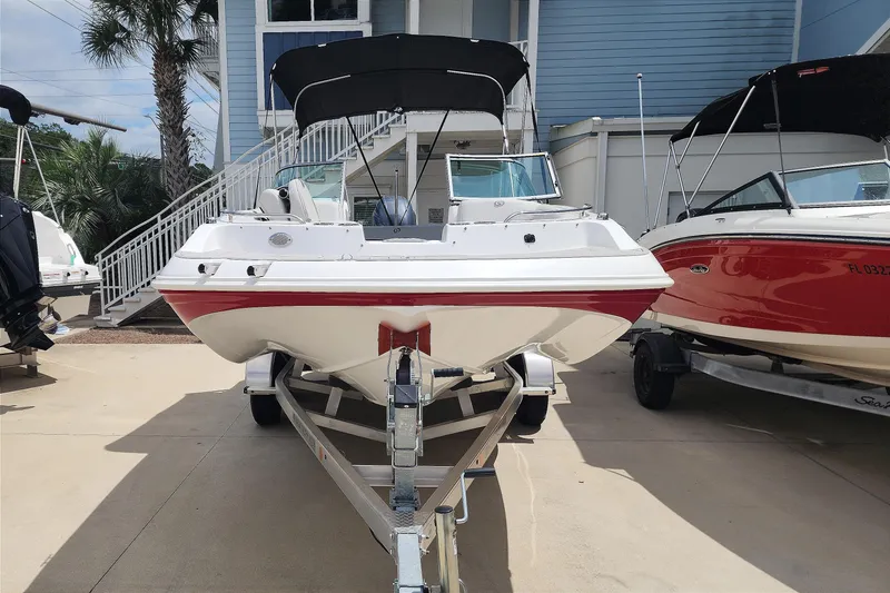 Slide: The Image of 2023 Hurricane SunDeck 187 OB boat on trailer, white with red accents, parked outdoors. - 2
