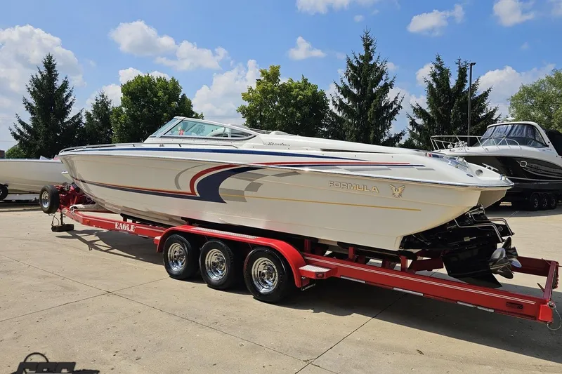 Slide: The Image of 2005 Formula 353 FASTech boat on red trailer, parked outdoors under blue sky. - 25