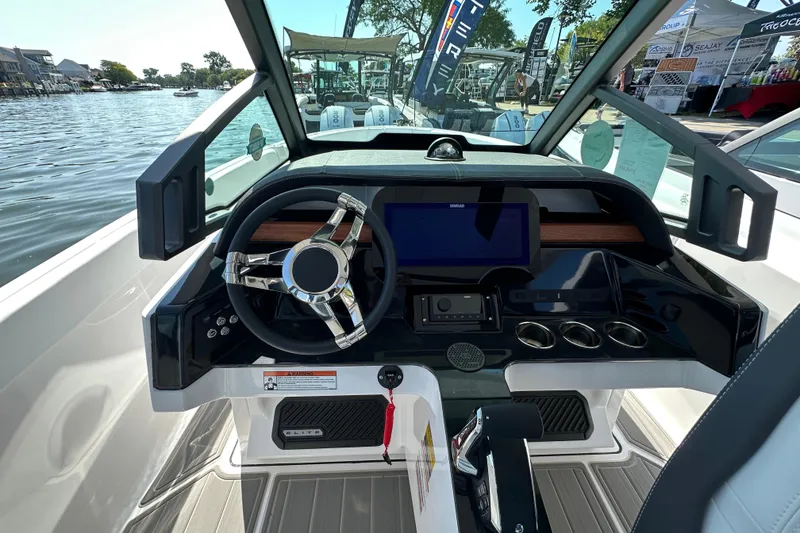 Slide: The Image of 2026 Monterey Elite 25 OB boat dashboard with steering wheel and digital display, docked by the water. - 10