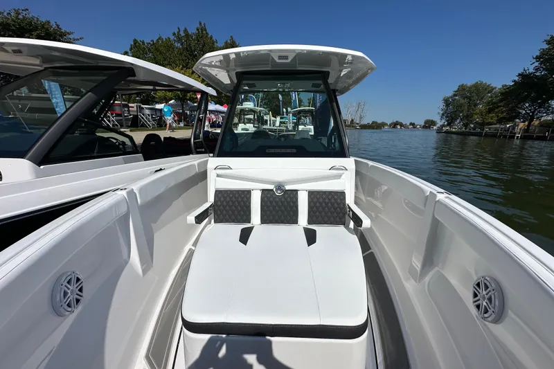 Slide: The Image of 2026 Monterey Elite 25 OB boat interior with seating, docked by a scenic lake. - 13