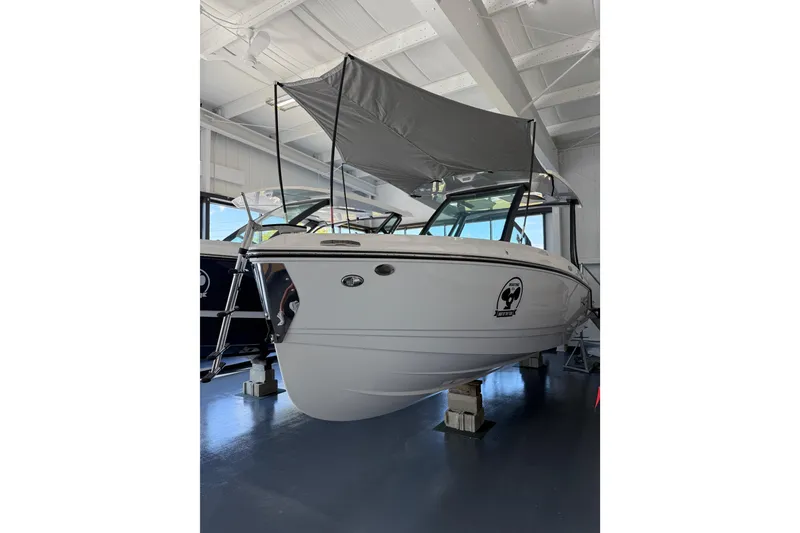 Slide: The Image of 2026 Monterey Elite 25 OB boat with canopy in showroom. - 2