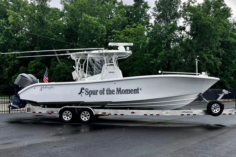 Slide: The Image of 2020 Yellowfin 32 Offshore boat on trailer, named "Spur of the Moment," parked outdoors. - 12