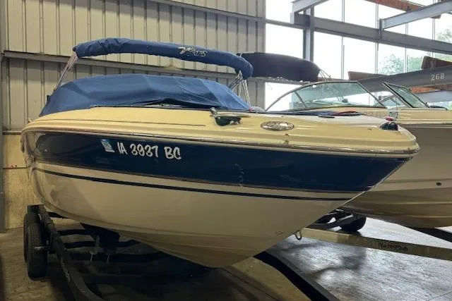 The Image of 2003 Sea Ray 220 Bow Rider boat with blue cover on trailer in storage facility. - 1