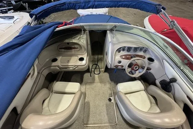 Slide: The Image of 2003 Sea Ray 220 Bow Rider interior with beige seating and blue canopy. - 6