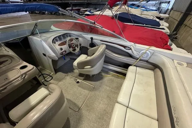 Slide: The Image of 2003 Sea Ray 220 Bow Rider interior with beige seating and dashboard in storage. - 7
