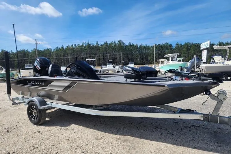 Slide: The Image of 2023 Lowe Stinger 178 boat on trailer, parked outdoors under blue sky. - 13