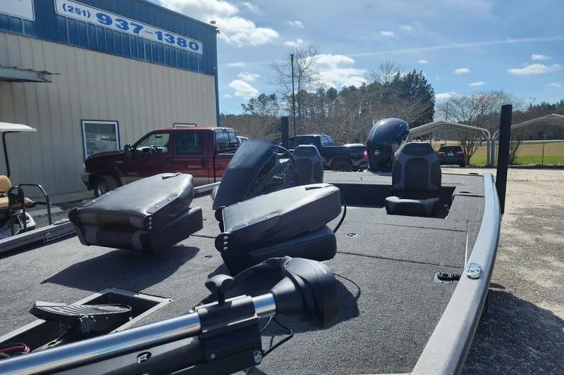 Slide: The Image of 2023 Lowe Stinger 178 boat with seats and motor, parked outdoors under a clear sky. - 9