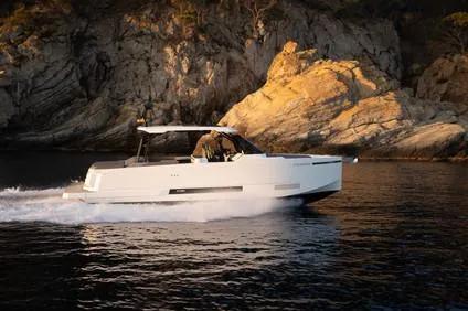 The Image of 2025 De Antonio Yachts D36 OPEN cruising near rocky coastline at sunset. - 1