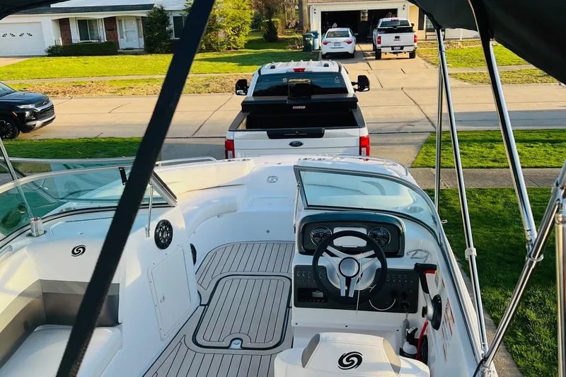 Slide: The Image of 2022 Hurricane SunDeck 187 IO boat interior with steering wheel, parked in a residential driveway. - 6