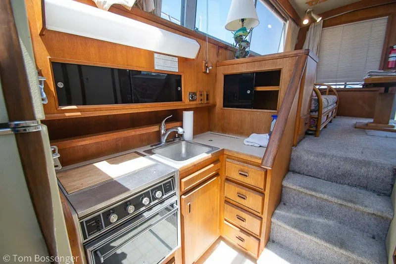 Slide: The Image of 1986 Bertram 42 Convertible yacht interior with wooden kitchen and cozy seating area. - 16