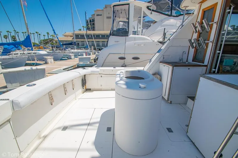 Slide: The Image of 1986 Bertram 42 Convertible yacht deck at marina, featuring fishing rod holders and seating. - 24